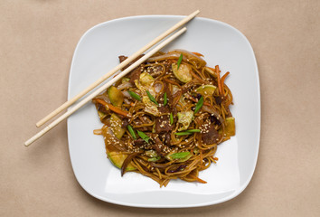 Chinese noodles with beef on a white plate in a restaurant