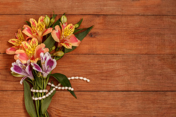 a small bouquet of Alstroemeria with a pearl thread on a wooden background