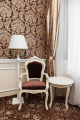 Classic royal furniture in a room. Lamp, table and armchair
