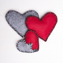 Three felt hearts on a white wooden background, valentines composition