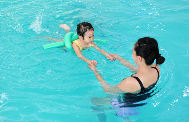 Close up mother teaching kid in swimming pool.