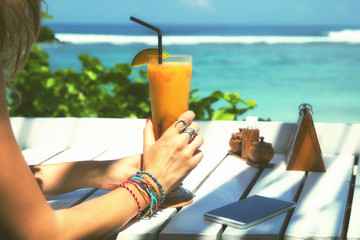 Young attractive girl drinking healthy juice on the beach.