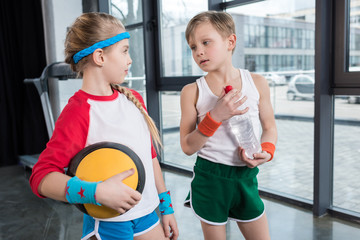 little boy and girl in sportswear talking at fitness studio, children sport concept