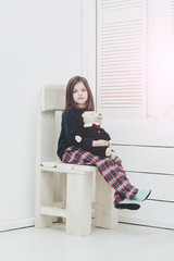 Pretty girl with cute teddy bear toy sitting on chair