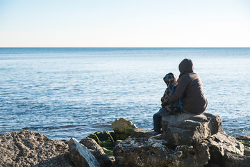 Back view of a mother and his son walking on the sea shore