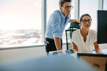 Corporate professionals looking at computer monitor in office