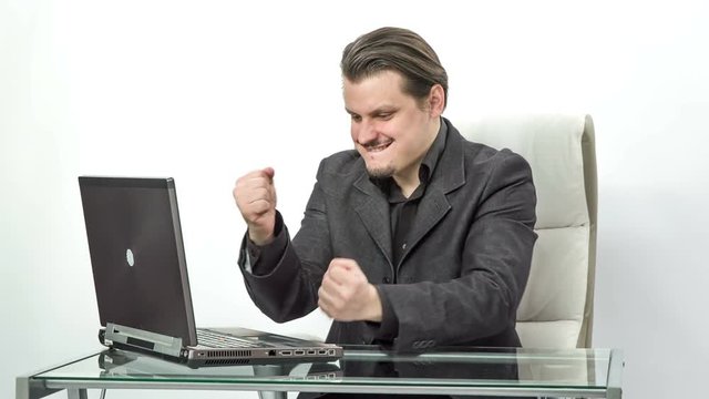 The worker in the office is really happy about something. He stops typing on his computer and expresses his joy and excitement.