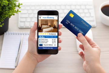 female hands holding phone app hotel booking and credit card