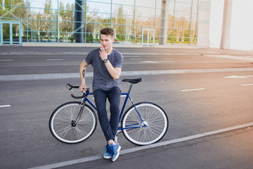 Fototapeta premium Yong man with fixie bike near big Shop-window smoke a cigarette