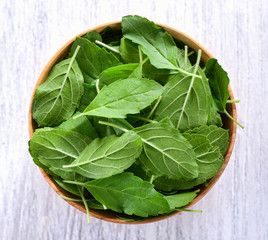 Basil leaves in a wooden bowl
