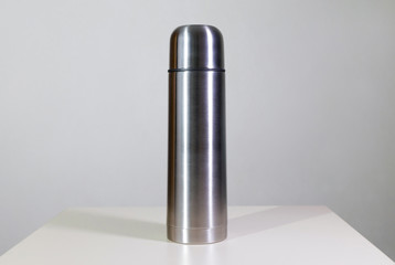 Metal vacuum flask.
Closeup of a stainless steel vacuum flask and its cup on white background.