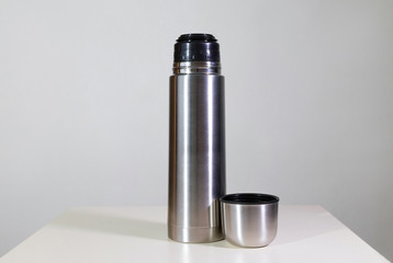 Metal vacuum flask.
Closeup of a stainless steel vacuum flask and its cup on white background.
