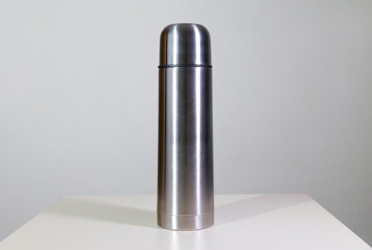 Metal vacuum flask.
Closeup of a stainless steel vacuum flask and its cup on white background.