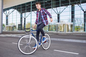 Young man balancing on his fixed gear bicycle on the empty mall parcking 