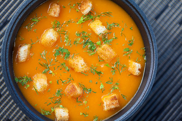 Pumpkin soup with croutons served in a black bowl