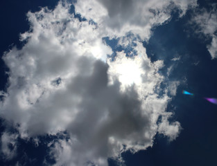 Panoramic image of the sun behind the clouds on the blue sky background. 