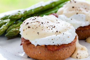 Poached eggs with bacon and cheese sauce on top of integral bread bun