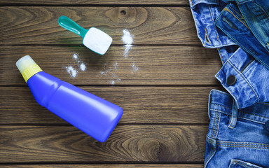 Pile of blue jeans clothes with detergent and washing powder, top view