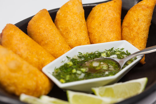 Typical Colombian empanadas served with spicy sauce on traditional black ceramic dish