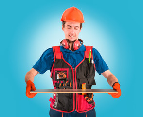 Handsome young handyman with a tool belt looking on a plate in hand. House renovation service. Building concept.