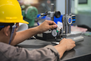 man measure part accuracy by dial guage