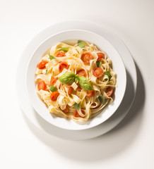dish with tagliatelle and tomatoes on the white background