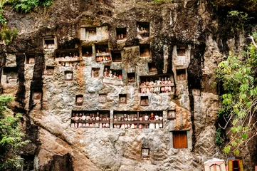 Photo sur Plexiglas Anti-reflet Indonésie Old torajan burial site in Lemo, Tana Toraja. The cemetery with coffins placed in caves carved into the rock and balconies with dressed wooden statues tau tau. Rantapao, Sulawesi, Indonesia