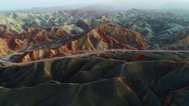 Aerial view on grass-covered sandstone hills in front of a colorful Rainbow Mountain in a Geopark. Part 3 of a 3 part series which can be merged to a continuous movie. 