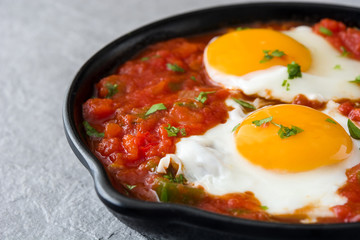 Mexican breakfast: Huevos rancheros in iron frying pan on gray stone
