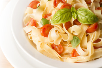 dish with tagliatelle and tomatoes on the white background