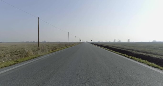 aerial empty paved road in rural fields. forward follow 4k drone video