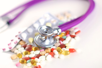 Close up of pills spread over the table with stethoscope and heart lying beside