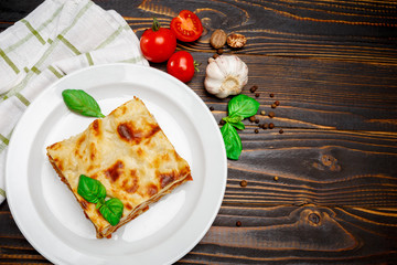 Portion of tasty lasagna on wooden backgound