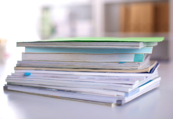 A stack of documentation is on the desktop in the office