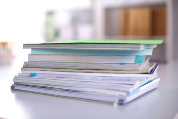 A stack of documentation is on the desktop in the office