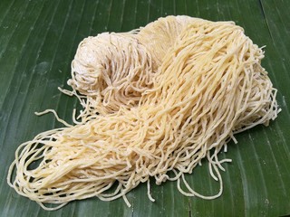 Egg noodles on banana Leaves in kitchen, Raw fresh yellow thin egg noodle,Raw uncooked homemade Chinese egg noodles