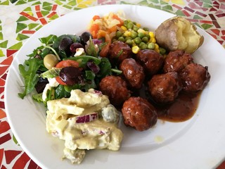 Meatballs with fresh vegetable and potato salad, jacket potato,Roasted meatballs in Spicy sweet and sour tomato sauce on white plate with soft boiled cabbage carrot,corn and bean, foreground focused