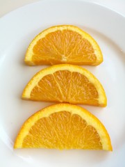 Orange slice isolated on white plate, 3 pieces of fresh sliced orange fruit with skin collection on top view