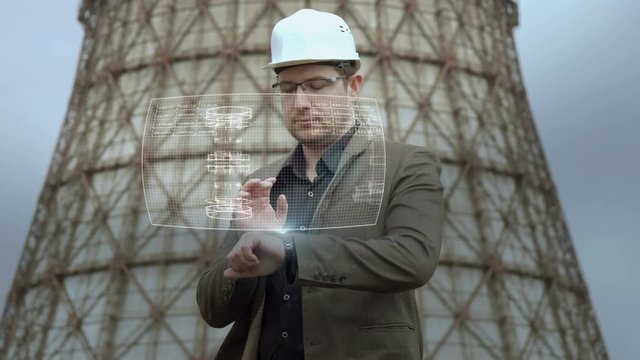 architect uses a holographic computer to work on the drawings. A young male engineer with a smart clock with a holographic screen. The future is already here. Futuristic smart watch technology
