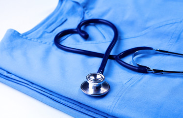 Medical stethoscope twisted in heart shape lying on patient medical history list and blue doctor uniform closeup