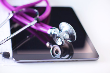 Tablet computer with a stethoscope lie on a table