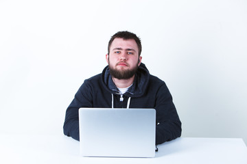 The programmer works behind the laptop. Isolated, one person on a white background. He is calm.