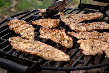 Grilling chicken fillets at a barbecue