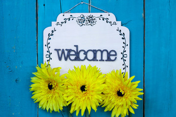 Welcome sign with yellow spring flowers hanging on rustic antique teal blue door