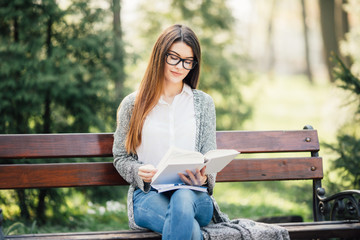 Obraz premium serious young, beautiful girl holding an open book, read background summer green park