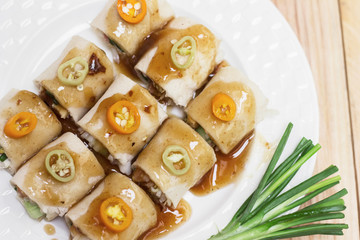 Fresh spring rolls and vegetables eaten on wooden table.