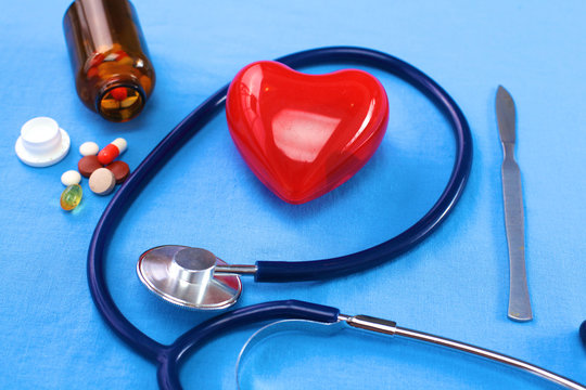 Close up of pills spread over the table with stethoscope and heart lying beside