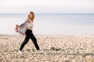 Blonde girl on the beach of the sandy beach by the sea