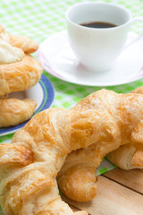 Coffee with fresh croissant breakfast on wooden table.