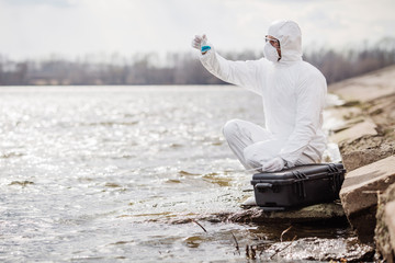 Scientist or biologist wearing protective uniforms examining the liquid contents of a test tube. .